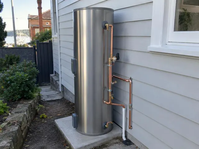 Outdoor hot water cylinder with copper pipework beside a weatherboard house in Clovelly