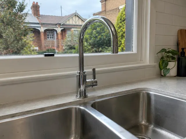 Chrome kitchen tap above a double sink with a window and tiled splashback in Waverley
